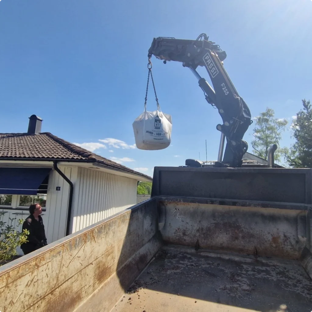 Kranen lyfter en storsäck över ett villatak, sett från flaket