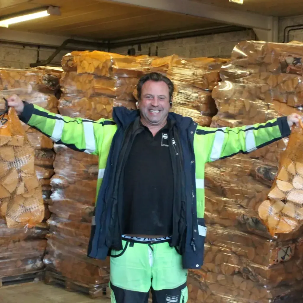 Thomas med utsträckta armar framför vedlagret